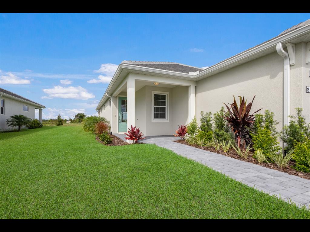 A paved walkway leads to the covered entryway of a beige house with a teal door — 1099 WATERLINE COURT, SARASOTA, FL
