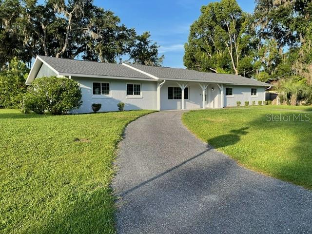 A single-story house with a light-colored exterior and a long driveway sits on a lawn — 2190 SE 39TH STREET, OCALA, FL