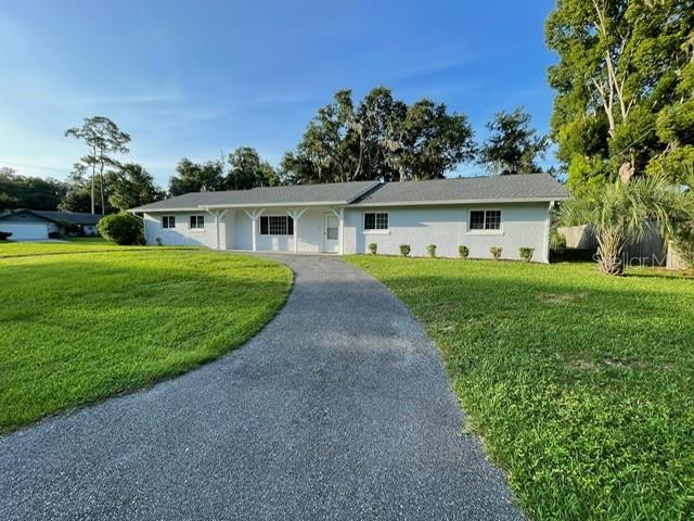 A single-story white house with a gray roof sits behind a long gravel driveway — 2190 SE 39TH STREET, OCALA, FL