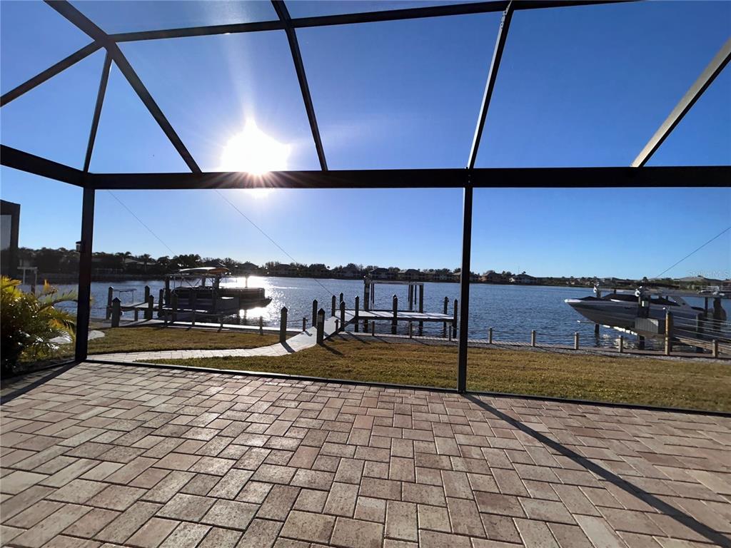 A view of a waterfront canal from a paved patio enclosed by a screen cage — 1022 OVERLOOK COURT, BRADENTON, FL
