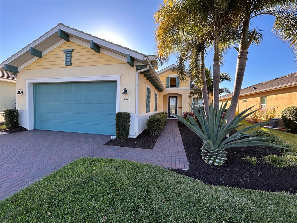 A yellow house with a blue garage door and a brick walkway leading to the entrance — 1022 OVERLOOK COURT, BRADENTON, FL