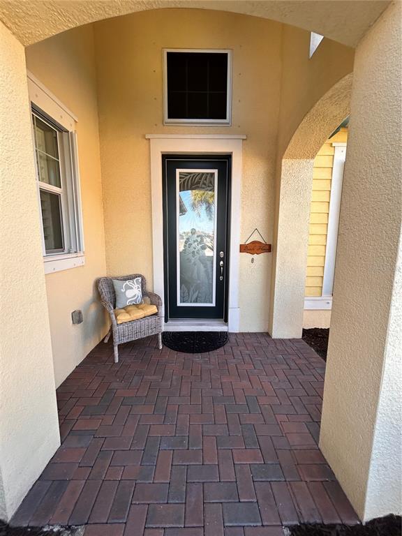 A covered front porch features a brick paver floor, a wicker chair, and a glass-paneled door — 1022 OVERLOOK COURT, BRADENTON, FL