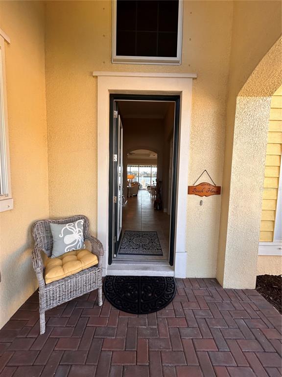 A wicker chair sits on a brick porch outside an open front door — 1022 OVERLOOK COURT, BRADENTON, FL
