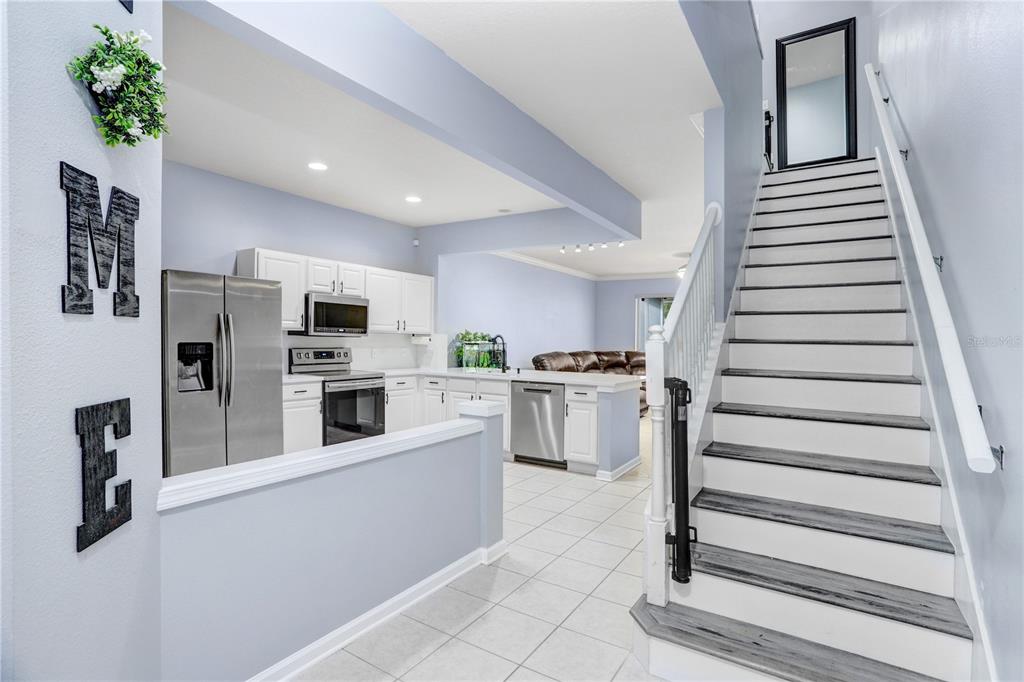 A view of a kitchen with white cabinets and stainless appliances next to a staircase — 4986 POND RIDGE DRIVE, RIVERVIEW, FL