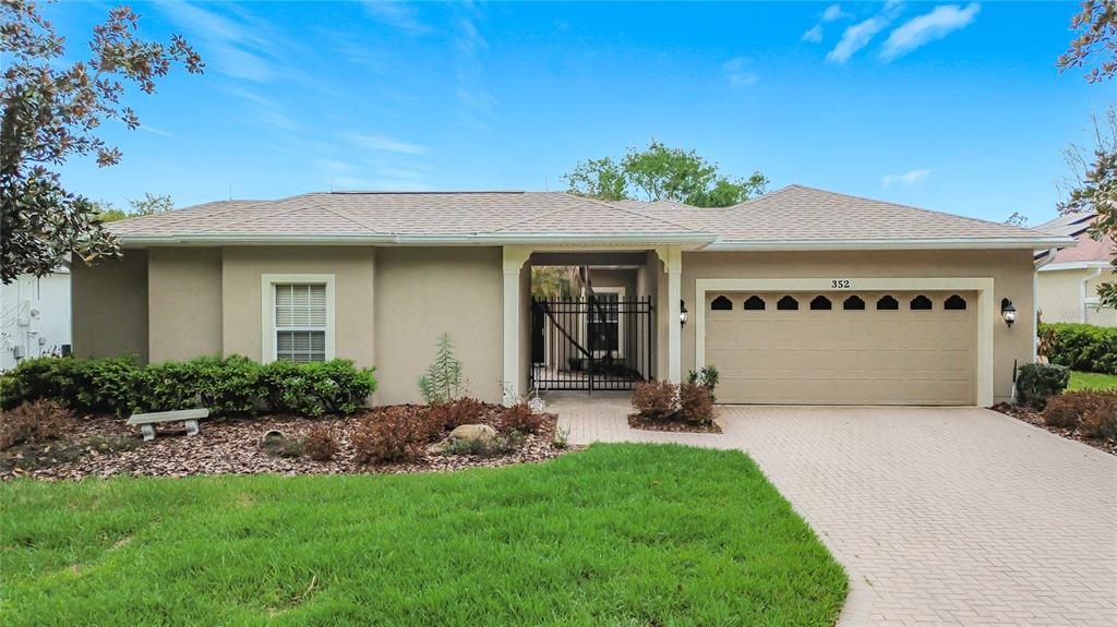A single-story house with a beige stucco exterior, a two-car garage, and a paved driveway — 352 HAMRICK DRIVE, KISSIMMEE, FL