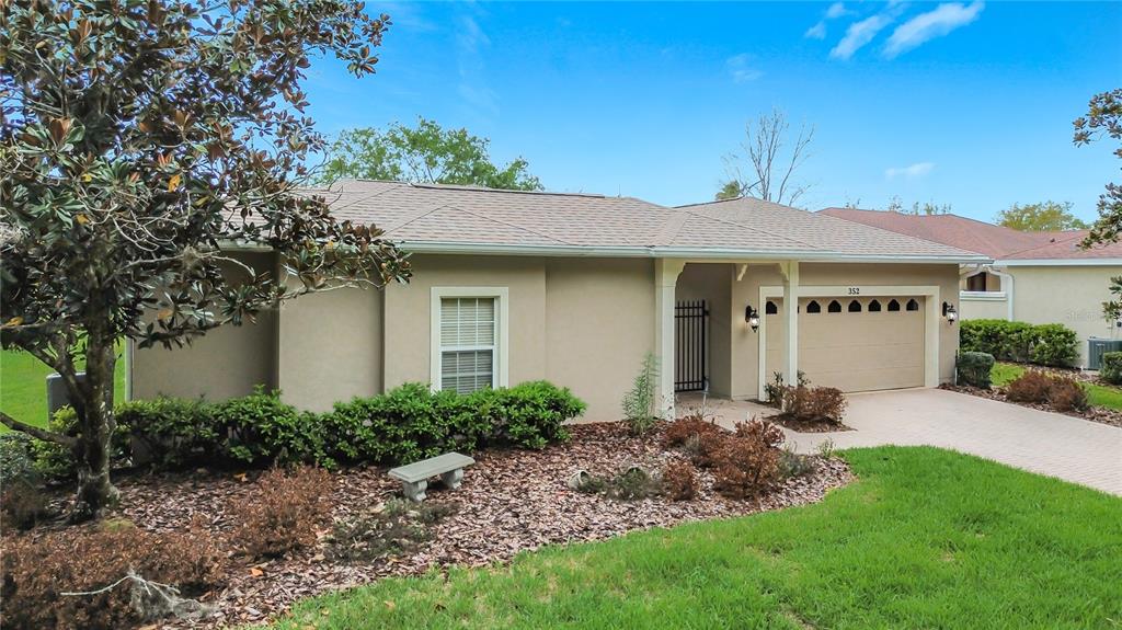 A single-story house with a beige exterior, a two-car garage, and a gated entryway — 352 HAMRICK DRIVE, KISSIMMEE, FL