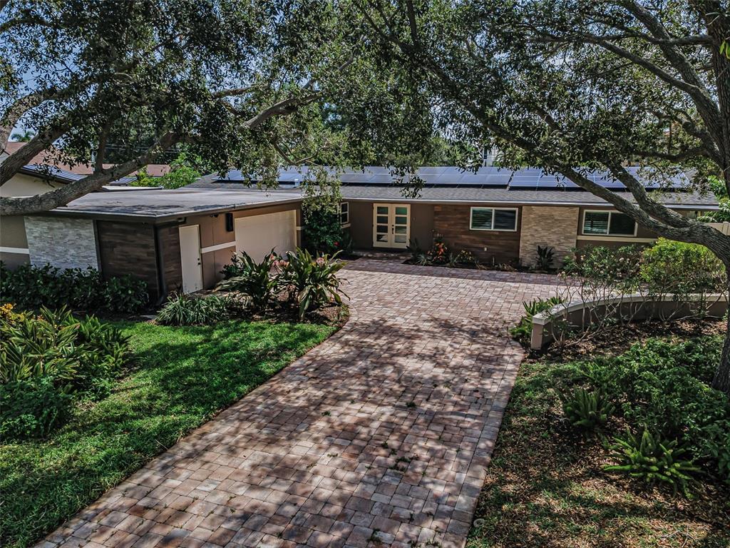 An exterior view of a single-story house with a paver driveway and rooftop solar panels — 861 RAFAEL BOULEVARD NE, ST PETERSBURG, FL