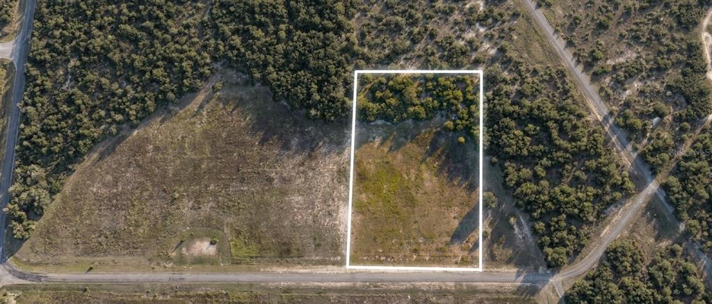 An aerial view shows a rectangular plot of land outlined in white amidst rural terrain — SE 136TH TERRACE, MORRISTON, FL
