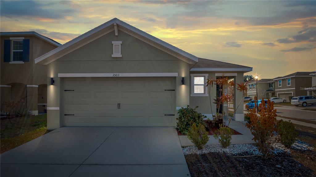 A single-story house with a two-car garage and a concrete driveway at sunset — 3503 DIAMOND LEAF COURT, VALRICO, FL
