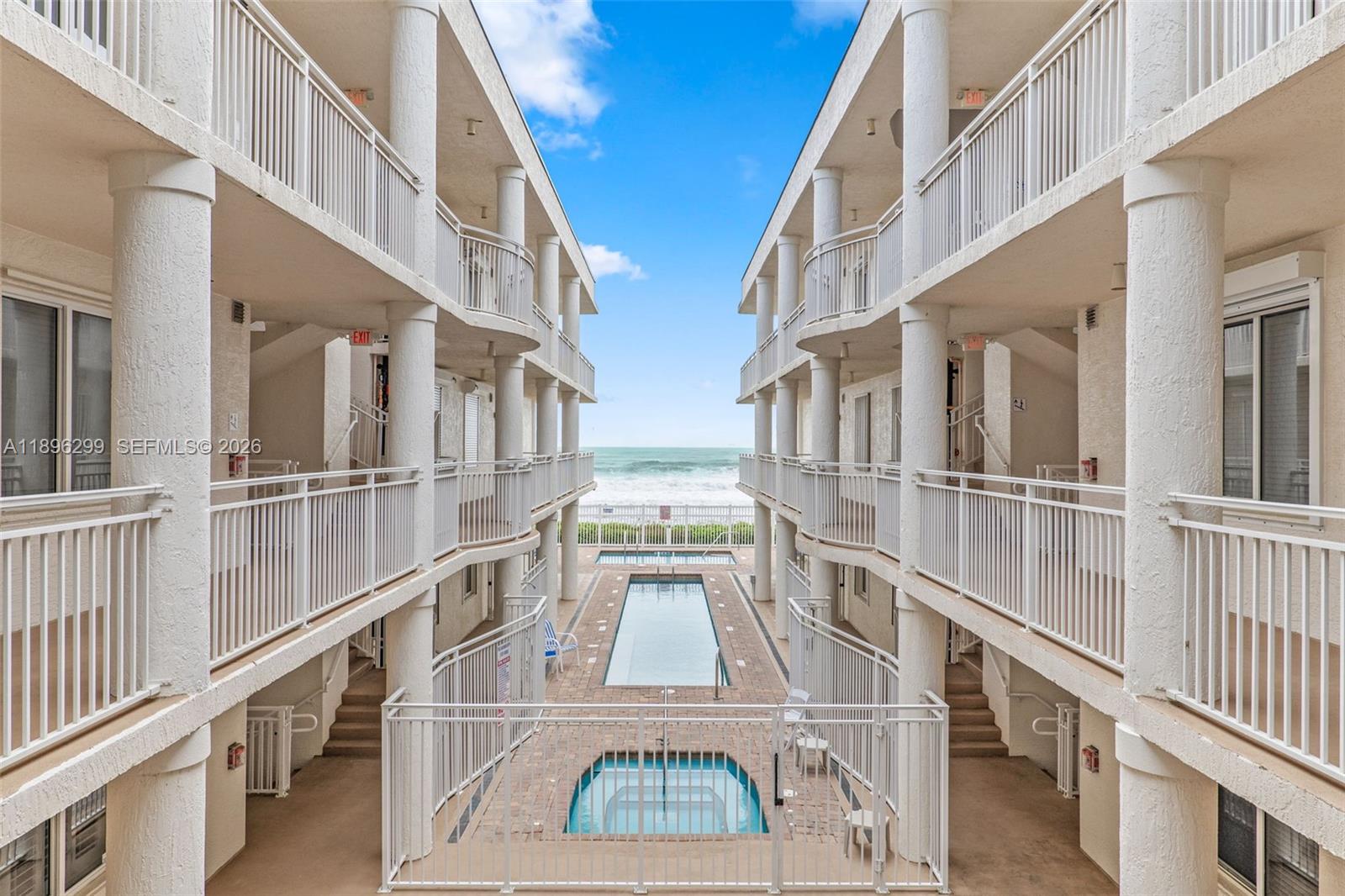 A view from between two apartment buildings looking toward a swimming pool and the ocean — 601 N Miramar # 107, Indialantic FL 32903, INDIALANTIC, FL