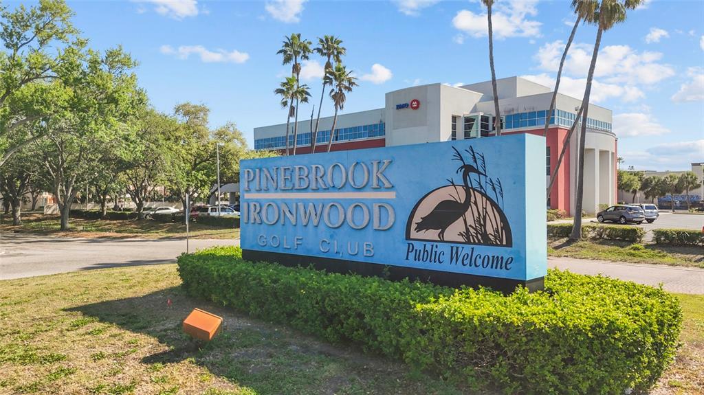 A blue sign for Pinebrook Ironwood Golf Club stands in front of a multi-story building — 4210 IRONWOOD CIRCLE UNIT 308J, BRADENTON, FL