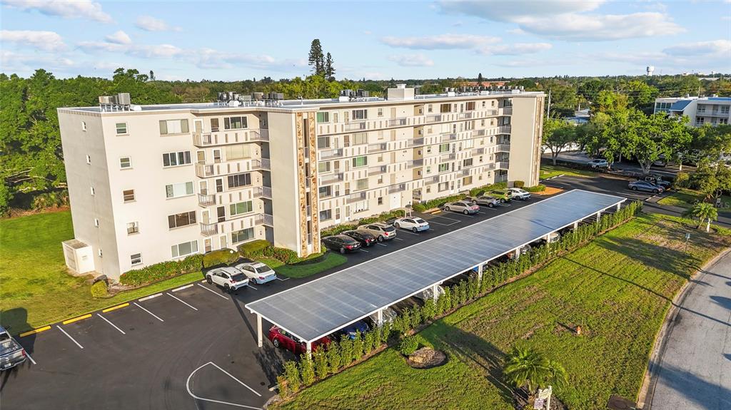 An aerial view shows a multi-story apartment building with a large covered parking structure — 4210 IRONWOOD CIRCLE UNIT 308J, BRADENTON, FL