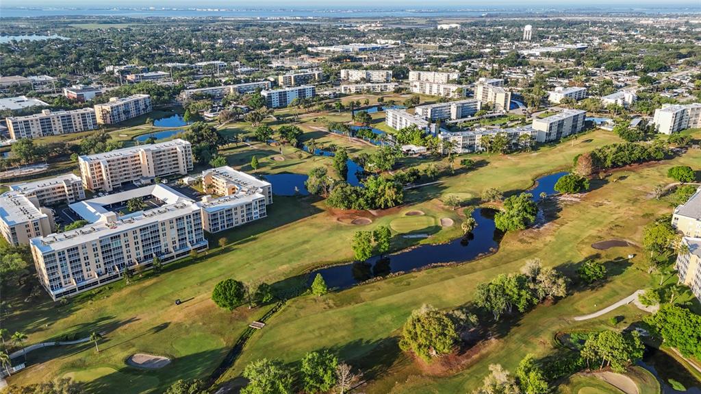 An aerial view shows multi-story apartment buildings surrounding a golf course with several ponds — 4210 IRONWOOD CIRCLE UNIT 308J, BRADENTON, FL