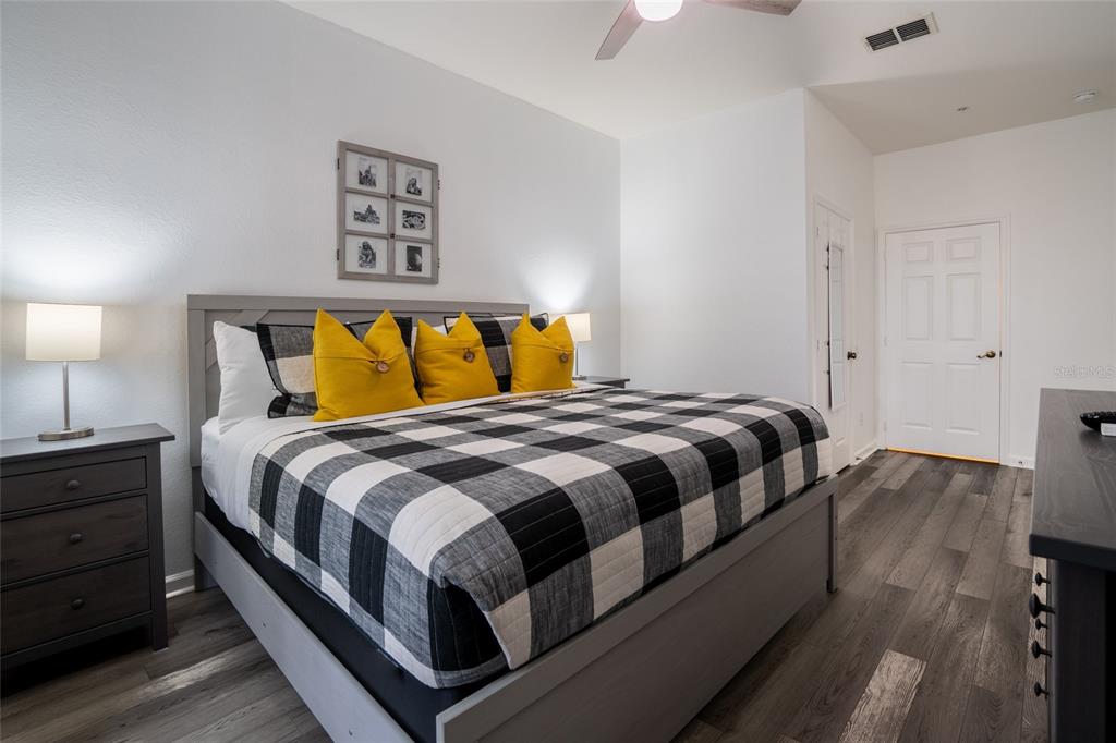 A bedroom features a bed with a black and white buffalo check comforter and yellow pillows — 2303 BUTTERFLY PALM WAY UNIT 303, KISSIMMEE, FL