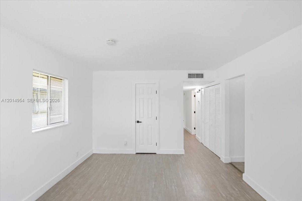This room features white walls, light-colored wood-look flooring, a window, and a white door — 921 NW 5th Ave, Pompano Beach FL 33060, POMPANO BEACH, FL