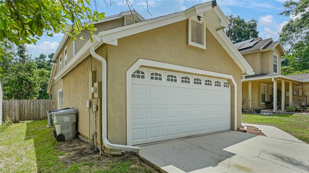 A tan stucco garage with a white sectional door and a concrete driveway — 1769 SADDLEBACK RIDGE ROAD, APOPKA, FL
