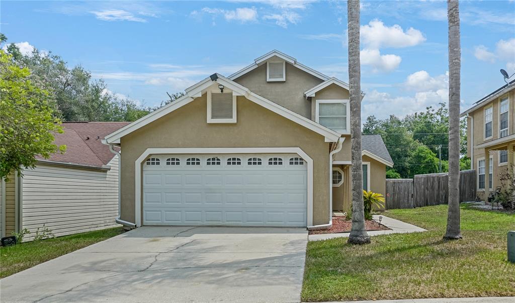 A two-story house with a beige stucco exterior, a two-car garage, and a concrete driveway — 1769 SADDLEBACK RIDGE ROAD, APOPKA, FL