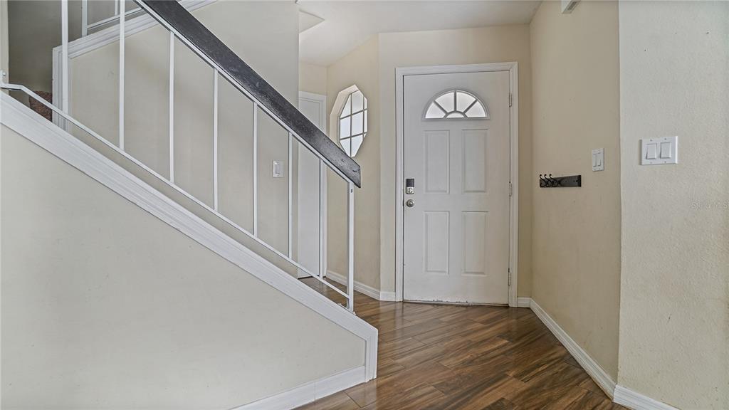 An entryway features wood-look flooring, a white front door, and a staircase with a dark railing — 1769 SADDLEBACK RIDGE ROAD, APOPKA, FL