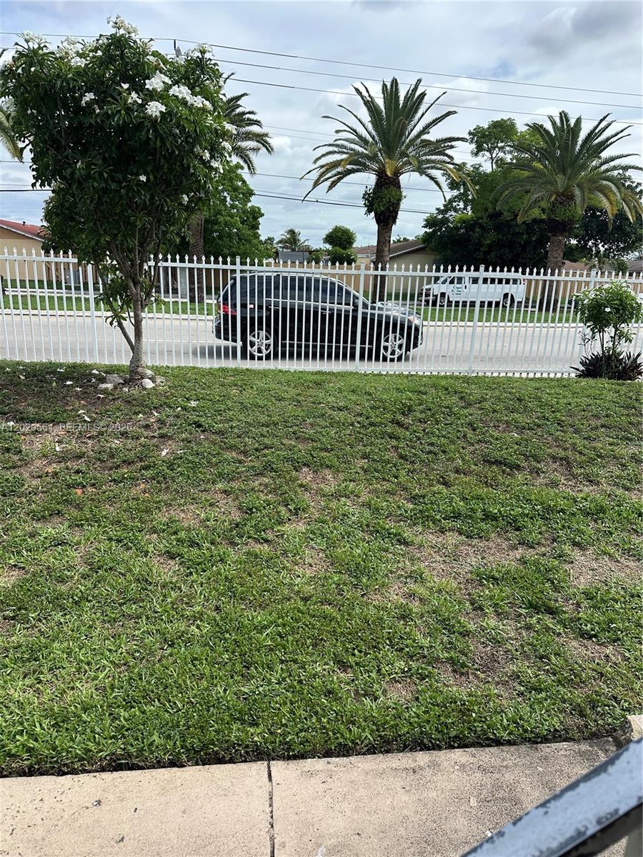 A white metal fence separates a grassy lawn from a street with parked vehicles — 15360 SW 72 ST # 21, Miami FL 33193, MIAMI, FL