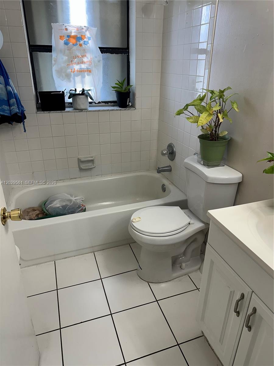 A bathroom features a white bathtub, a toilet, and a vanity with white tile flooring — 15360 SW 72 ST # 21, Miami FL 33193, MIAMI, FL