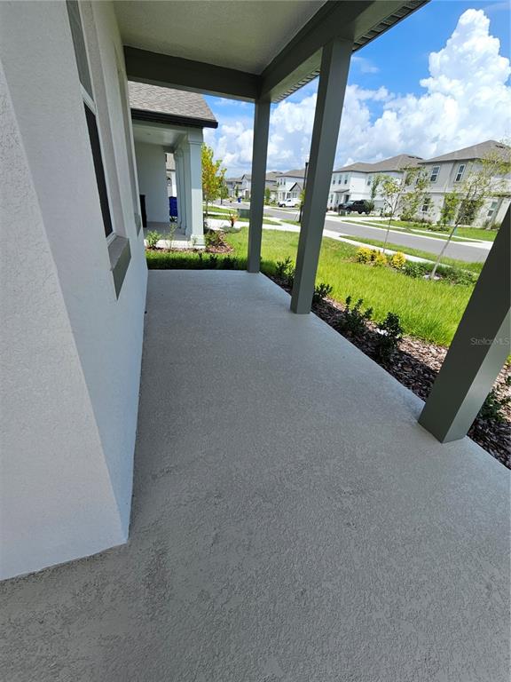 A covered concrete porch overlooks a suburban street with neighboring houses and green lawns — 5746 CATTLE RANCH DR, ST CLOUD, FL