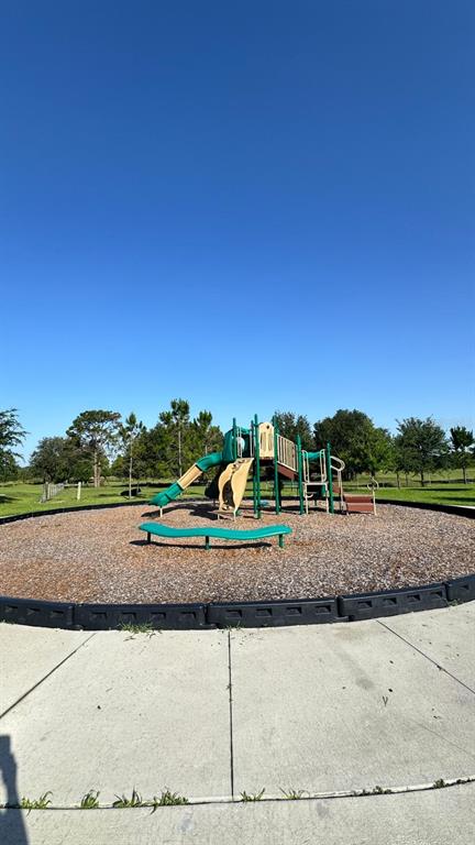 A playground with a slide and climbing structure sits on wood chips in a park — 5746 CATTLE RANCH DR, ST CLOUD, FL