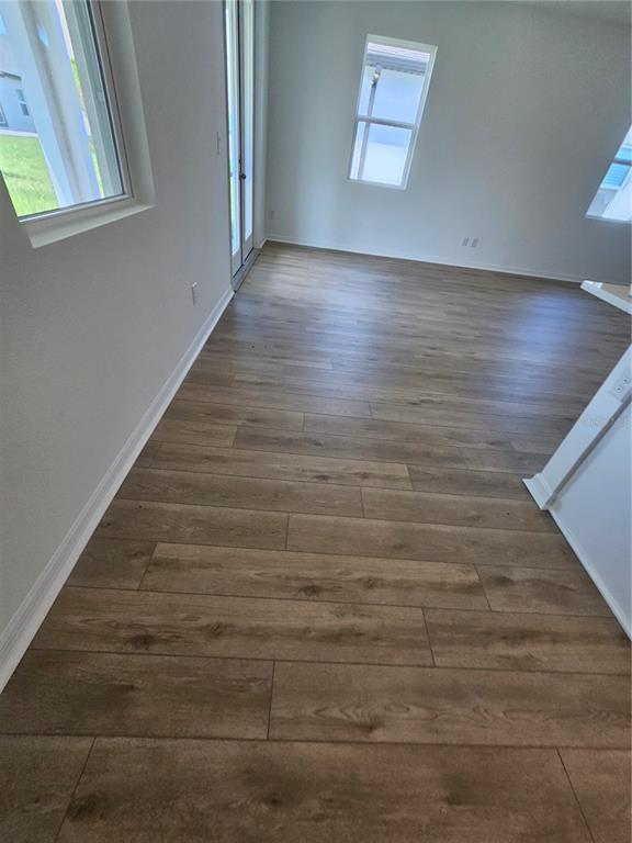 An empty room features light-colored walls, wood-look flooring, a glass door, and several windows — 5746 CATTLE RANCH DR, ST CLOUD, FL
