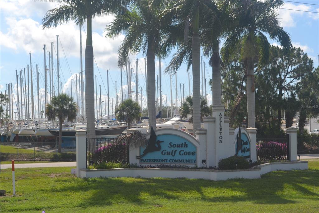 A sign for South Gulf Cove Waterfront Community stands before a marina filled with sailboats — 8410 TOPEKA CIRCLE, PORT CHARLOTTE, FL