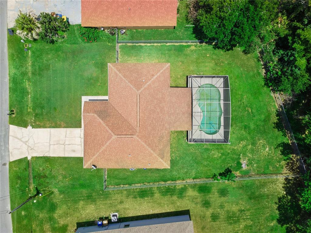 An aerial view shows a house with a shingled roof, a screened pool, and lawn — 909 SAN MARCO DR, KISSIMMEE, FL
