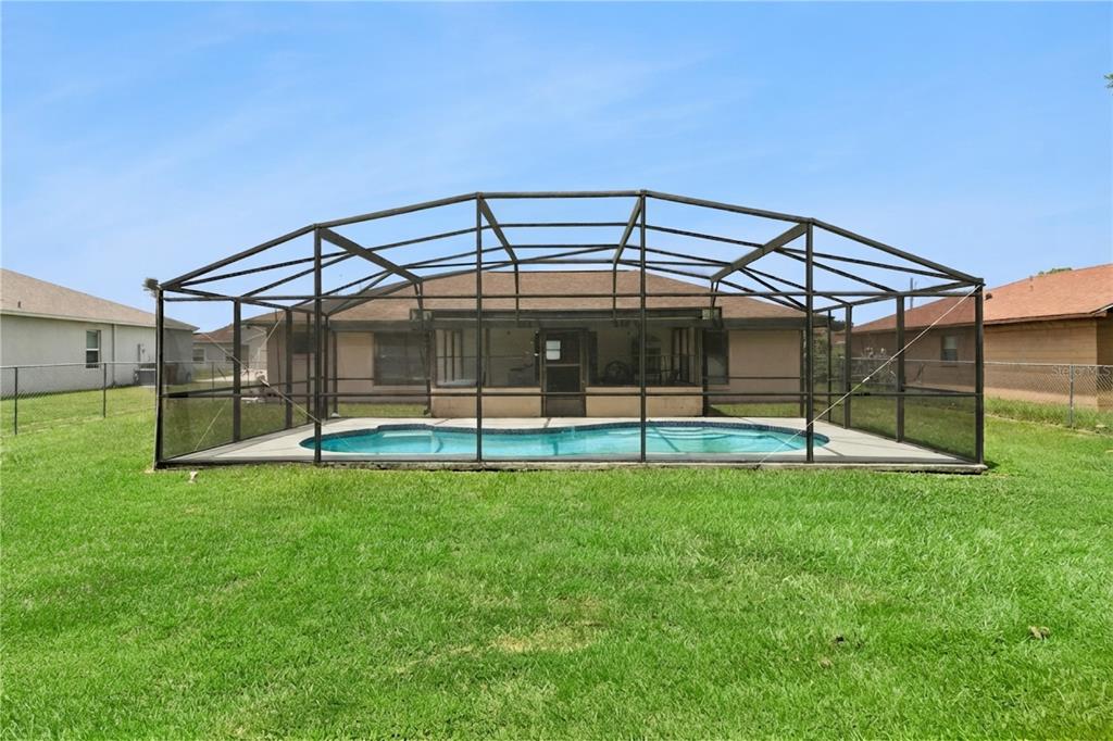 A backyard view of a house with a swimming pool enclosed by a screened lanai — 909 SAN MARCO DR, KISSIMMEE, FL