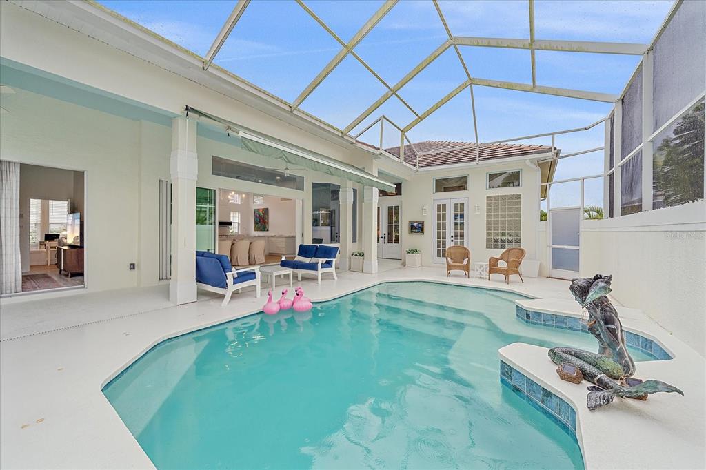 A screened-in pool area features a mermaid statue, patio furniture, and views into the home — 7507 ASCOT COURT, BRADENTON, FL