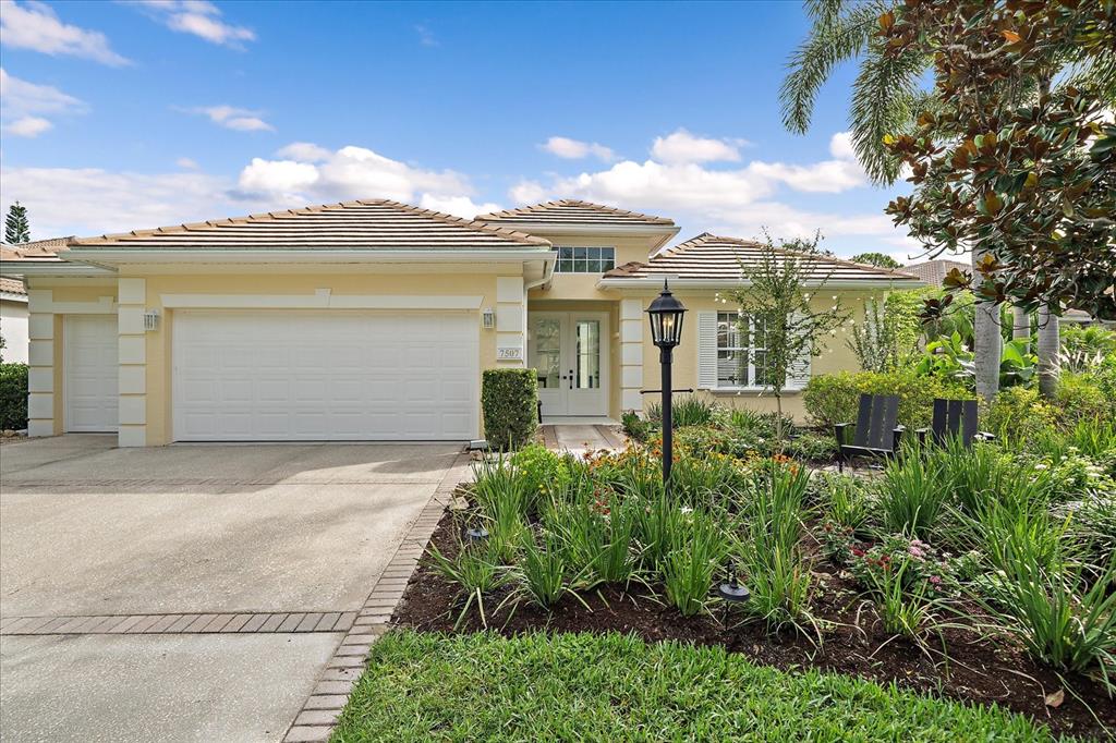 A single-story house with a yellow exterior, a two-car garage, and a landscaped front yard — 7507 ASCOT COURT, BRADENTON, FL