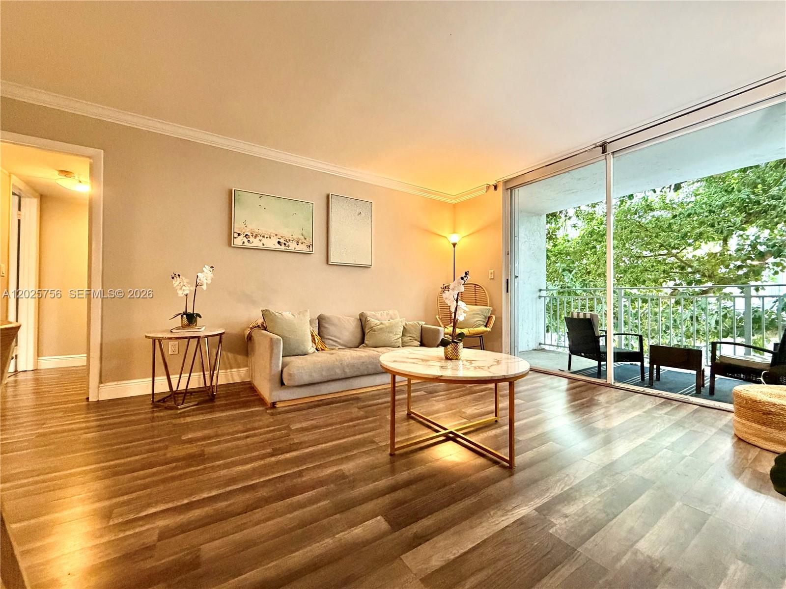 A living room features wood-look flooring, a sofa, a marble coffee table, and a balcony — 777 NE 62nd St # C512, Miami FL 33138, MIAMI, FL