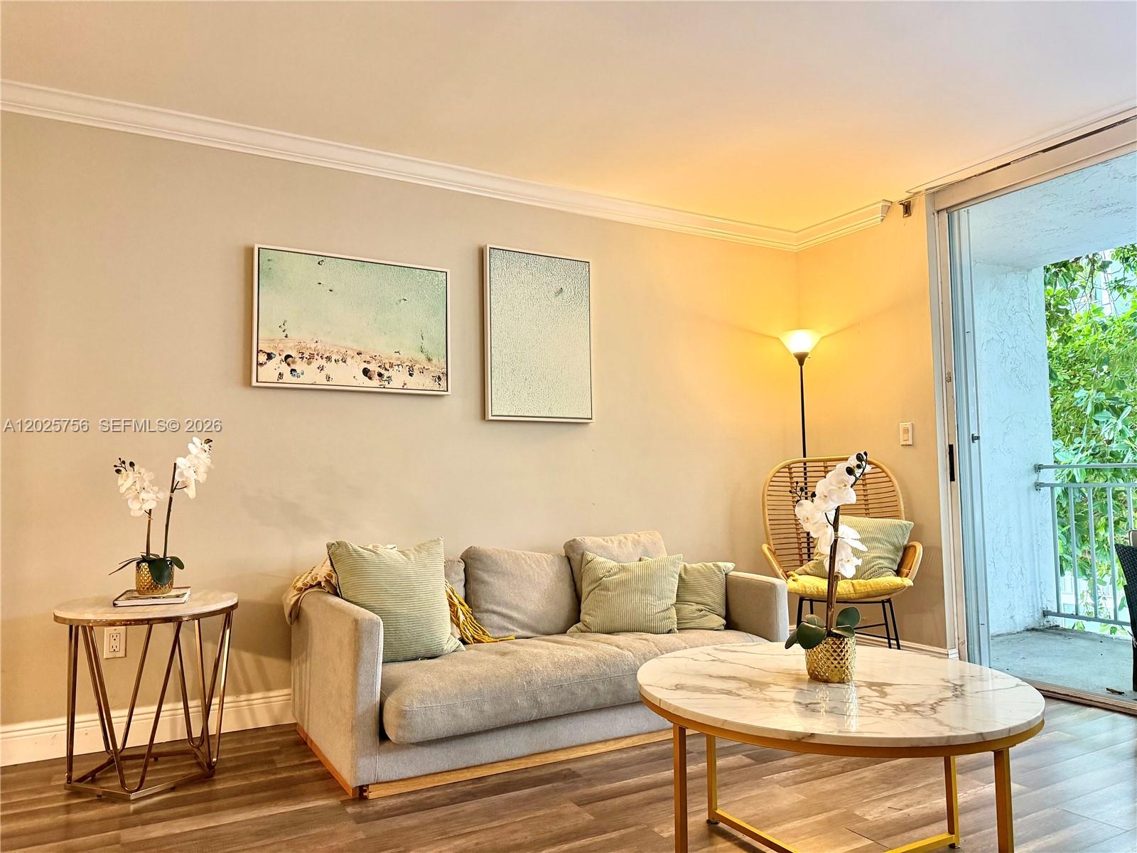 A living room features a gray sofa, marble-topped tables, and a sliding door to a balcony — 777 NE 62nd St # C512, Miami FL 33138, MIAMI, FL