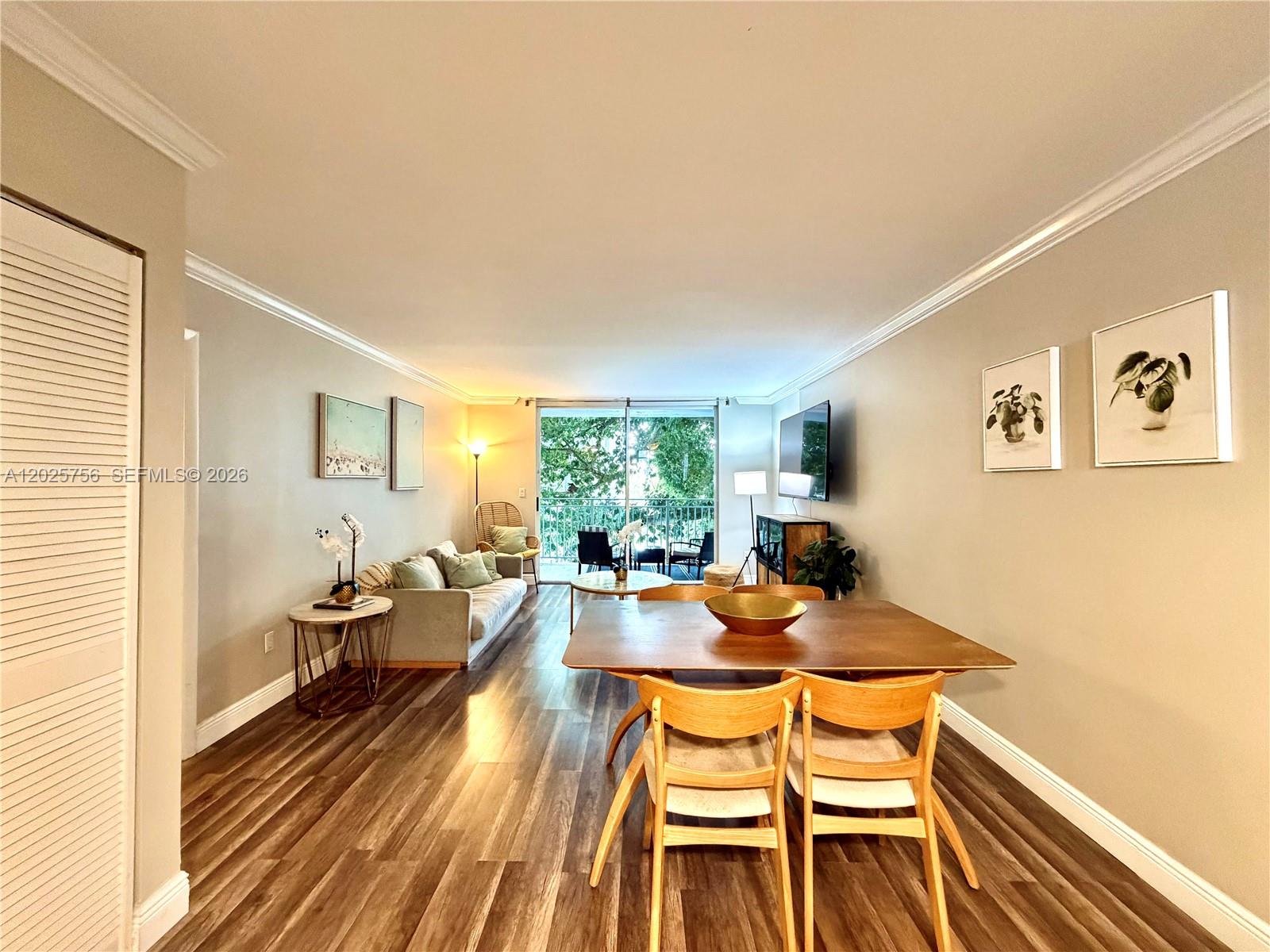 A living and dining area features wood-look flooring, neutral walls, and a sliding glass door — 777 NE 62nd St # C512, Miami FL 33138, MIAMI, FL