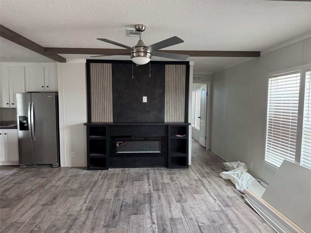 A living room features a black fireplace media console, wood-look flooring, and a ceiling fan — 20263 NW 304TH STREET, OKEECHOBEE, FL