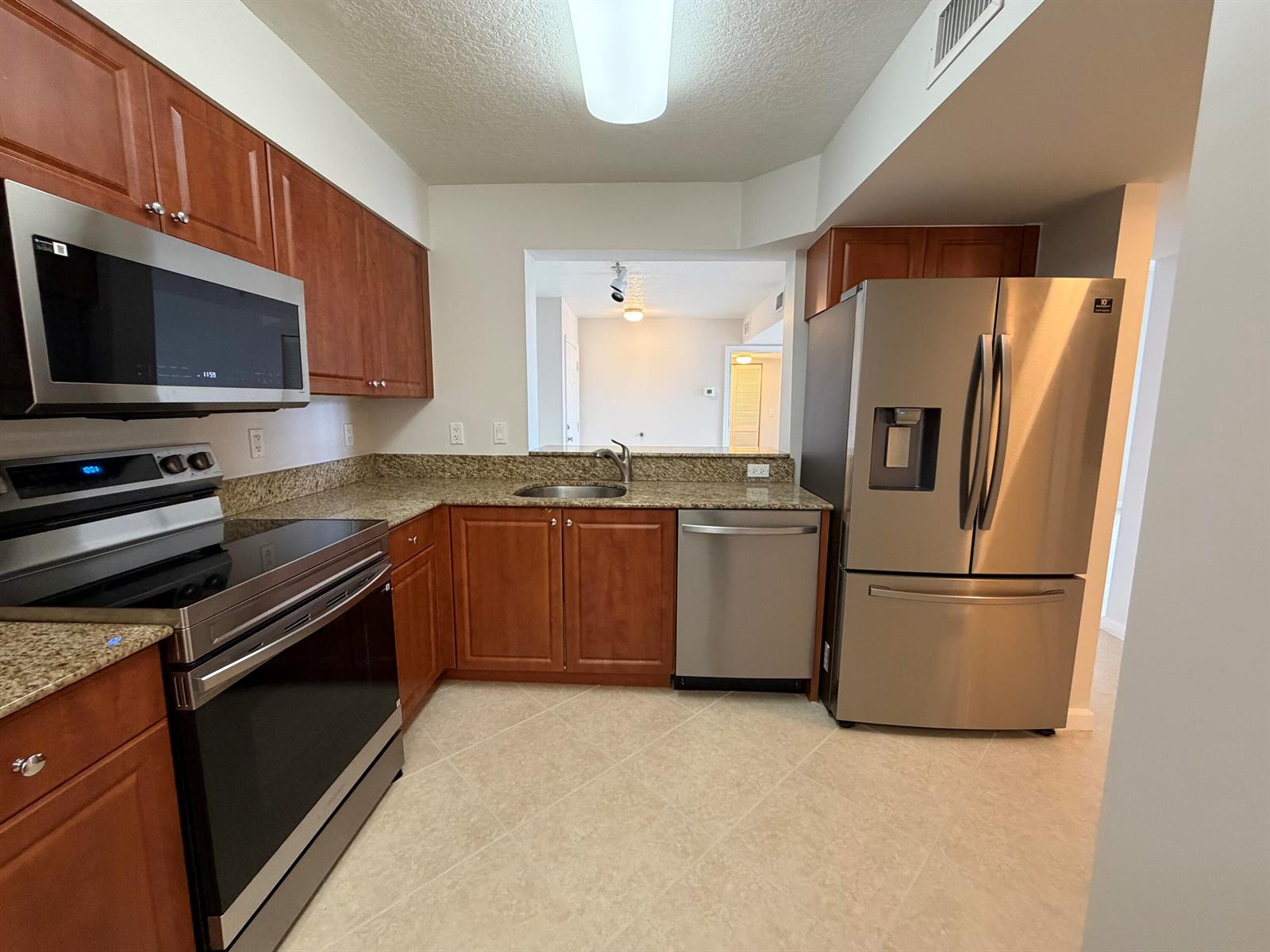 A kitchen features wood cabinets, granite countertops, stainless steel appliances, and tile flooring — 519 E Sheridan Street # 3072, Dania Beach FL 33004, DANIA BEACH, FL