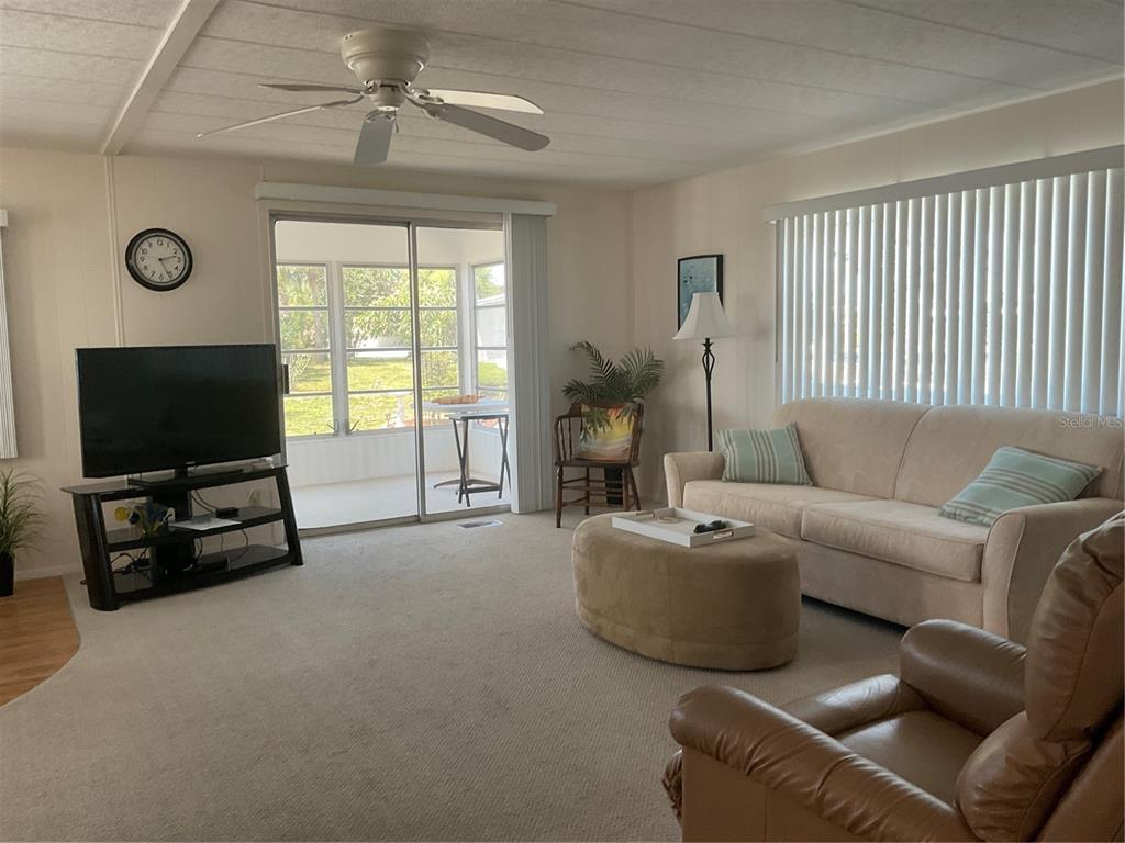 A living room features a beige sofa, an ottoman, a television, and a sliding glass door — 213 COMO DRIVE, VENICE, FL