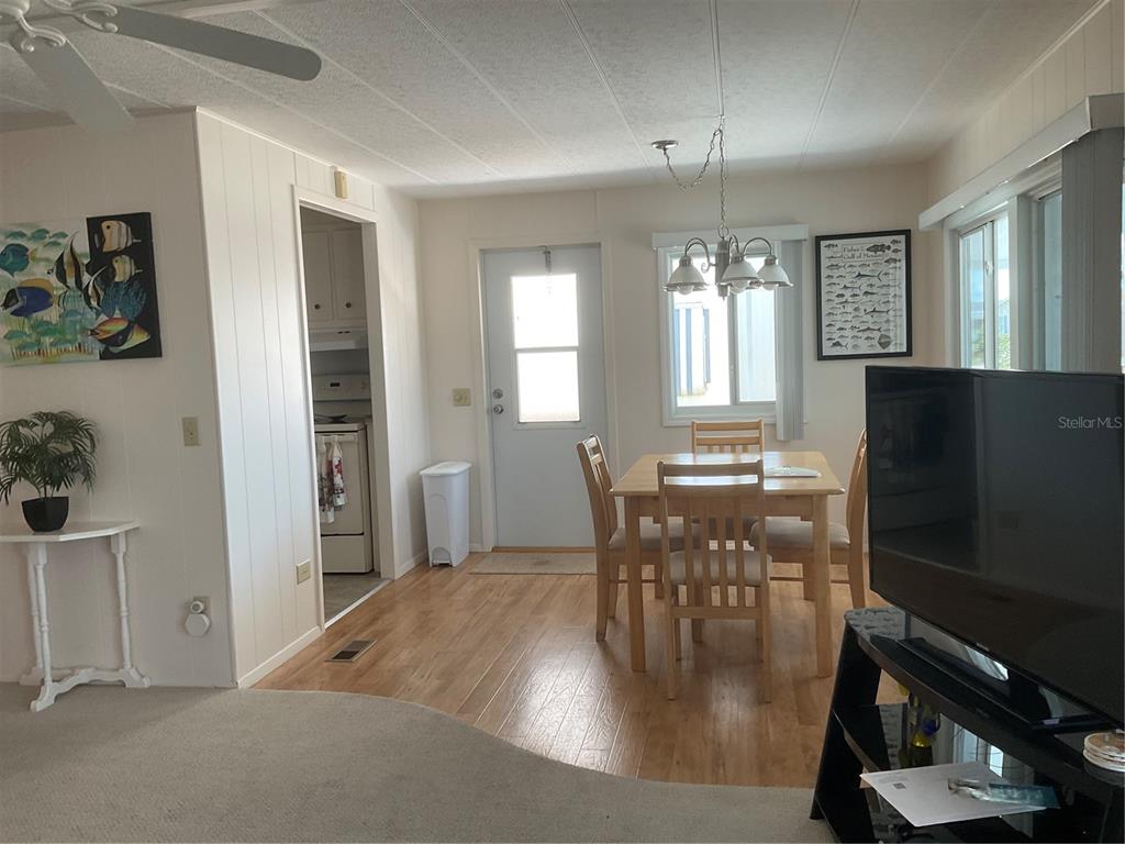 A dining area with a wooden table and chairs, adjacent to a kitchen and doorway — 213 COMO DRIVE, VENICE, FL