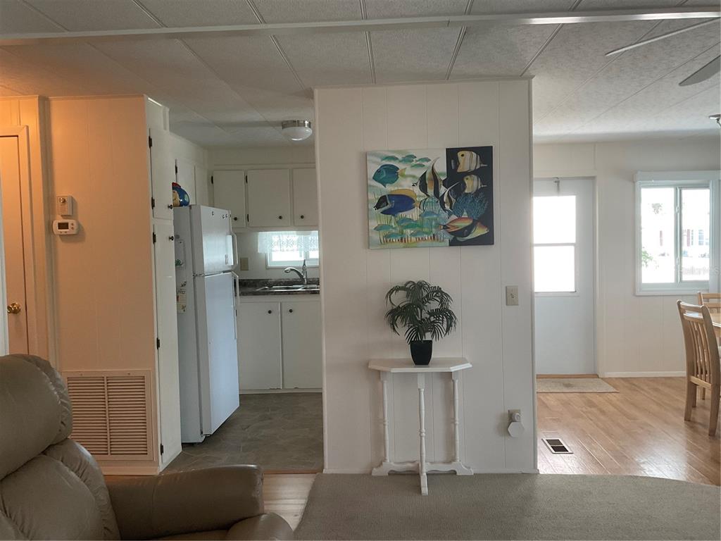 A view from a living area looking into a kitchen with white cabinets and appliances — 213 COMO DRIVE, VENICE, FL