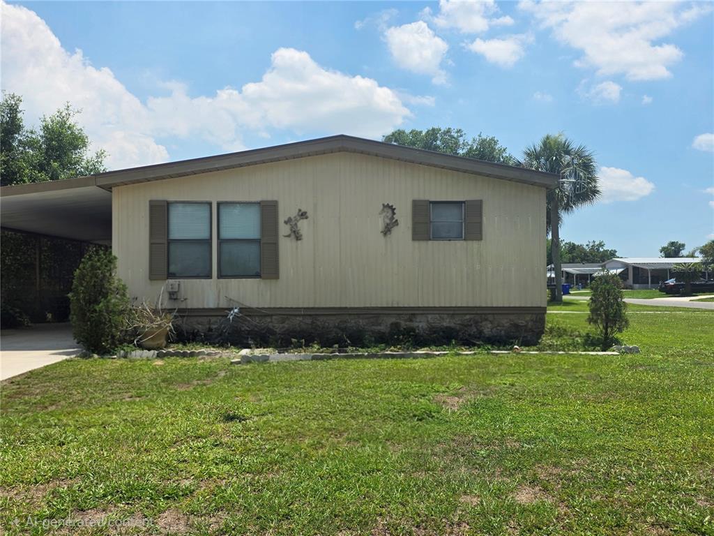 A single-story manufactured home with a carport and beige siding under a blue sky — 1855 BRAMBLEWOOD DRIVE, ST CLOUD, FL