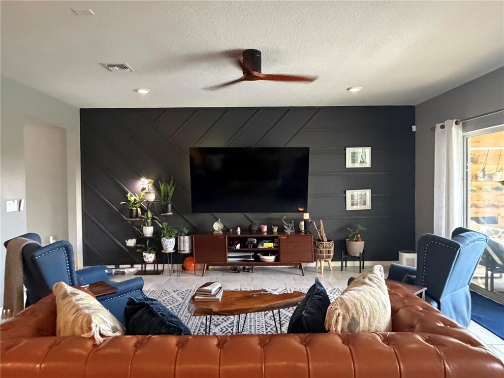 A living room features a dark accent wall with geometric molding, a television, and furniture — 9126 ROYAL RIVER CIRCLE, PARRISH, FL