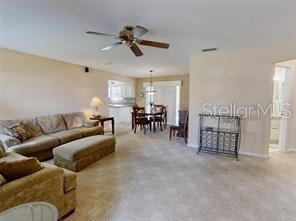 A living room with beige walls, tile flooring, a ceiling fan, and an adjacent dining area — 4544 NW 30TH PLACE, OCALA, FL