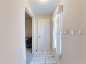 A hallway with white tiled flooring leads to a closed white door — 4544 NW 30TH PLACE, OCALA, FL