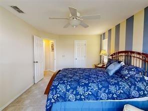 A bedroom features a bed with a blue floral comforter, a ceiling fan, and striped wallpaper — 4544 NW 30TH PLACE, OCALA, FL