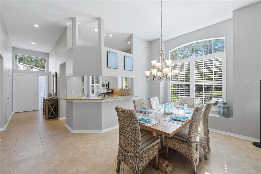 A dining room with a wooden table, wicker chairs, and a pass-through to the kitchen — 7906 WHITEBRIDGE GLEN, UNIVERSITY PARK, FL