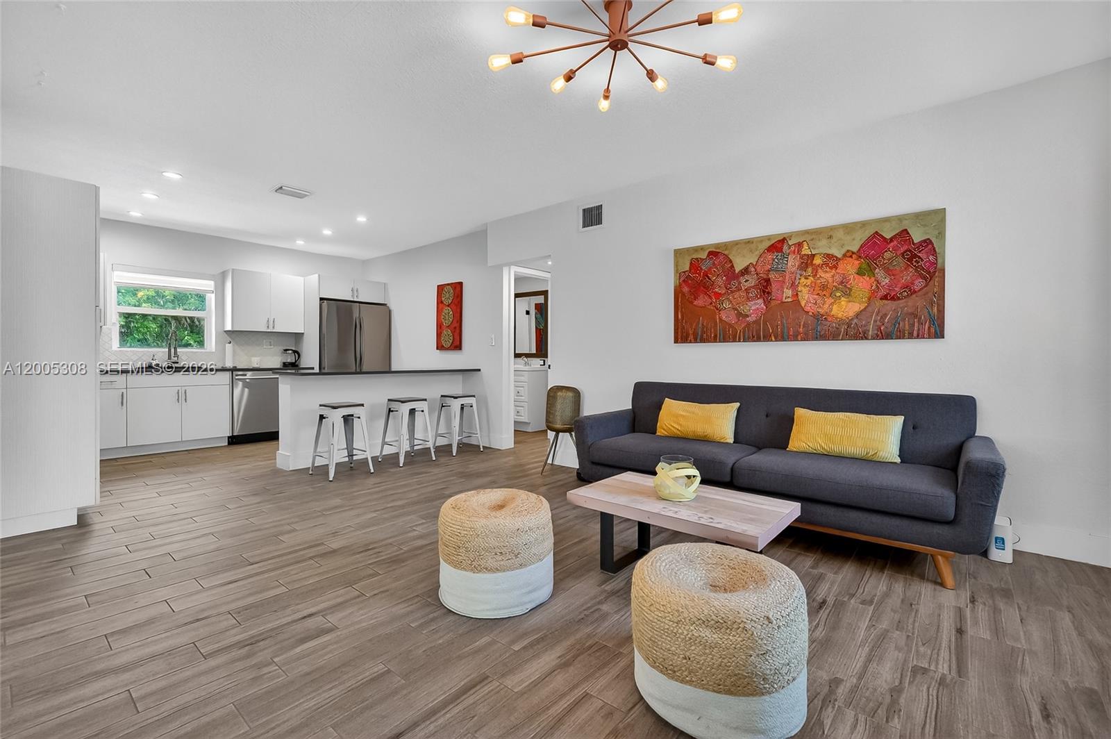 A split-level living area features a circular wall cutout, gray sectional sofa, and wood-look flooring — 541 NW 109th St, Miami FL 33168, MIAMI, FL