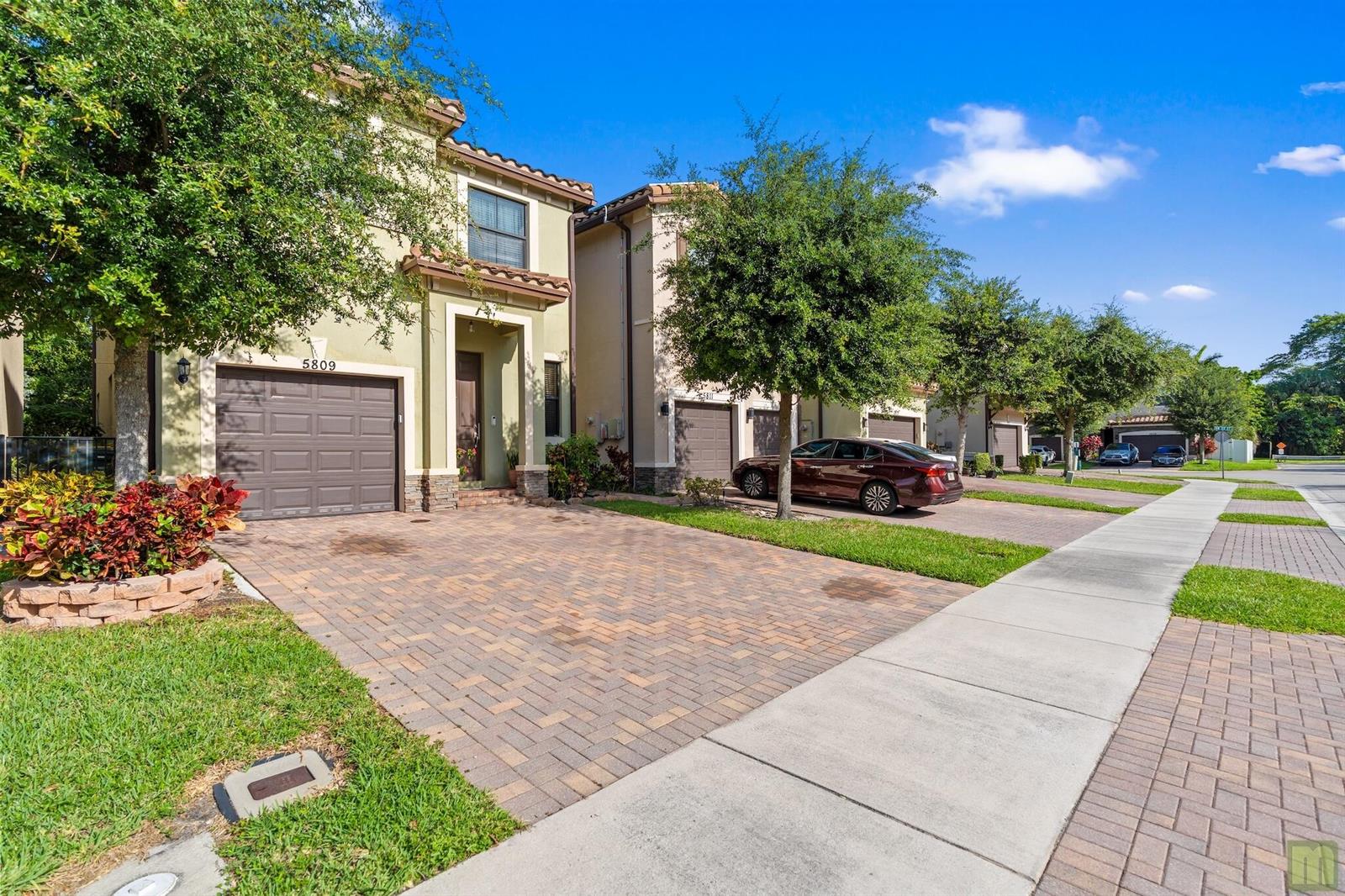 A row of two-story suburban townhomes with brick paver driveways and attached garages — 5809 NW 46th Lane, Tamarac FL 33319, TAMARAC, FL