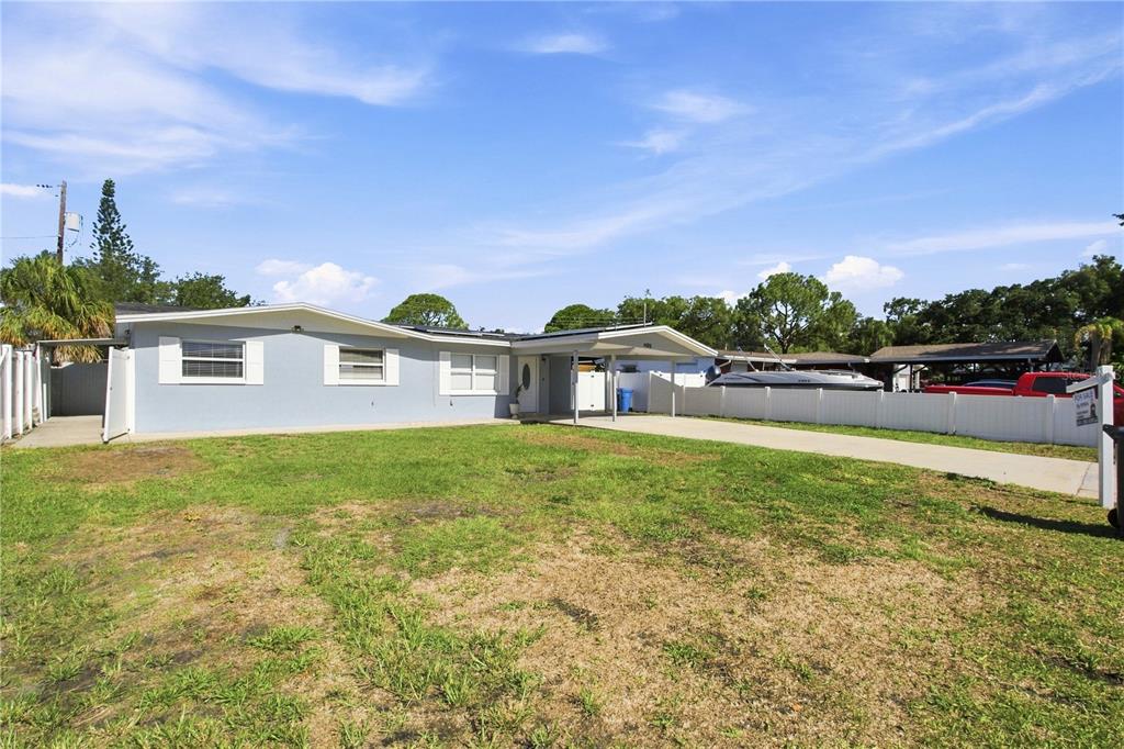 A light blue single-story house features a carport and a white vinyl privacy fence — 4606 BYERLE CIRCLE, TAMPA, FL
