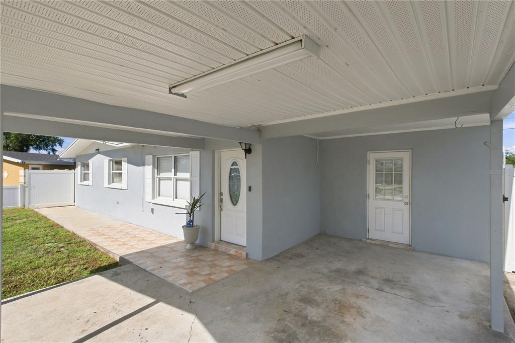 A covered carport area features a tiled walkway leading to a white front door — 4606 BYERLE CIRCLE, TAMPA, FL